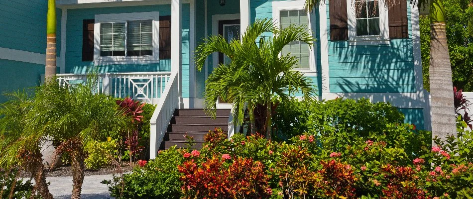 Blue house in New Smyrna Beach, FL, with tropical landscaping.