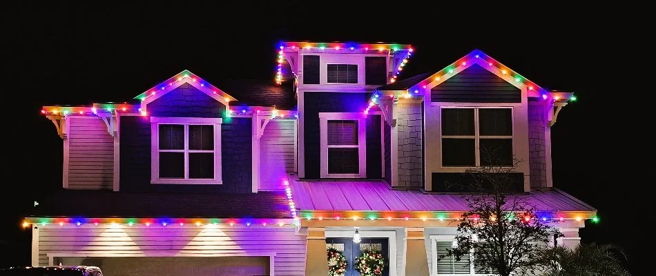 Two-story house in New Smyrna Beach, FL, with colorful holiday lights.