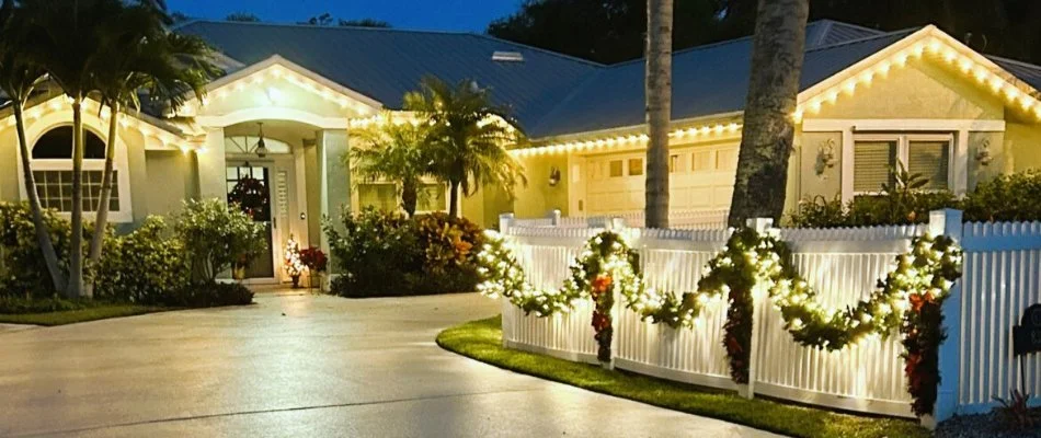 A home in New Smyrna Beach, FL, with a white fence and white holiday lights.