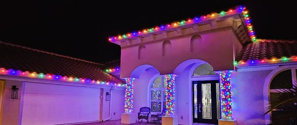 A home in New Smyrna Beach, FL, with columns and colorful holiday lights.