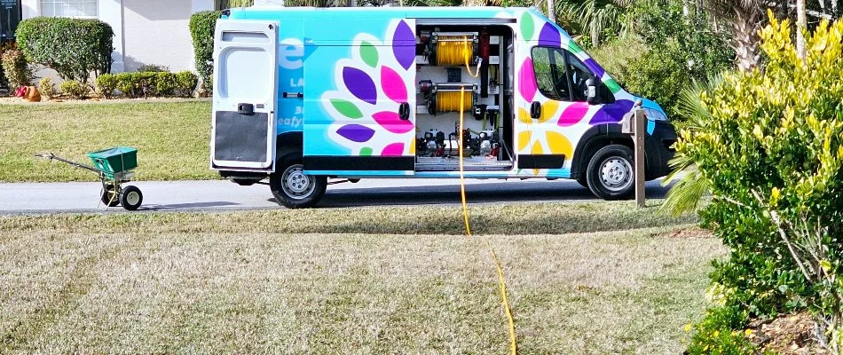 Leafy van in New Smyrna Beach, FL, with a yellow hose across a lawn.
