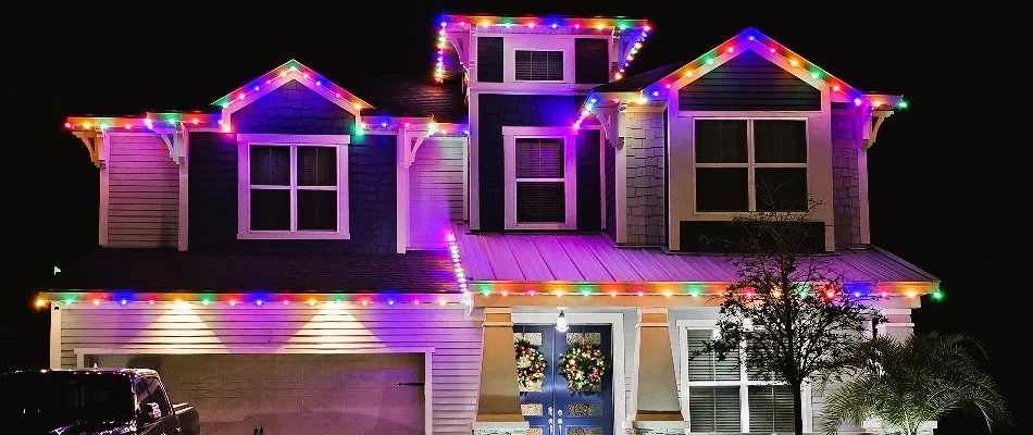 A two story home in New Smyrna Beach, FL, with colorful holiday lights and two wreaths.