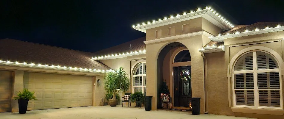 Home with garage in New Smyrna Beach, FL, decorated with warm white holiday lights.
