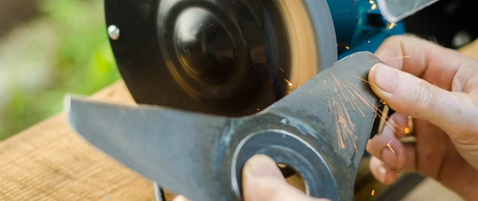 Person sharpening mower blade on a property in New Smyrna Beach, FL.